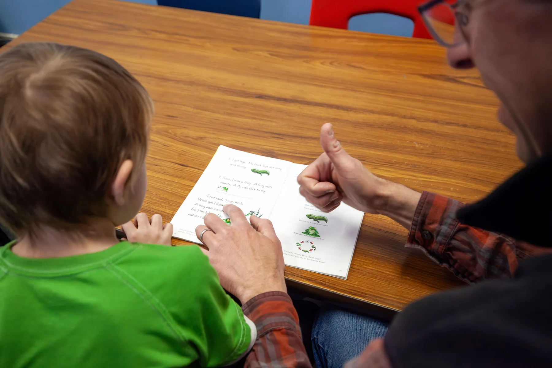 A ROW volunteer encouraging a young reader with a thumbs-up