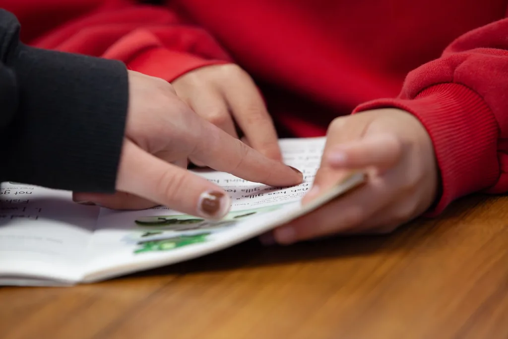 A volunteer and student point to words in a book together