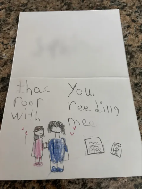 An open thank-you card with a child’s drawing of a student and ROW reader
