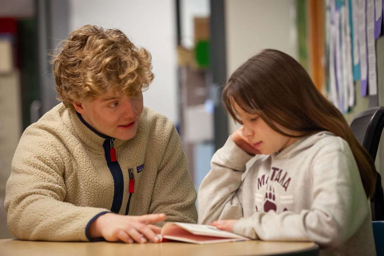 A ROW volunteer supporting a student as they read together