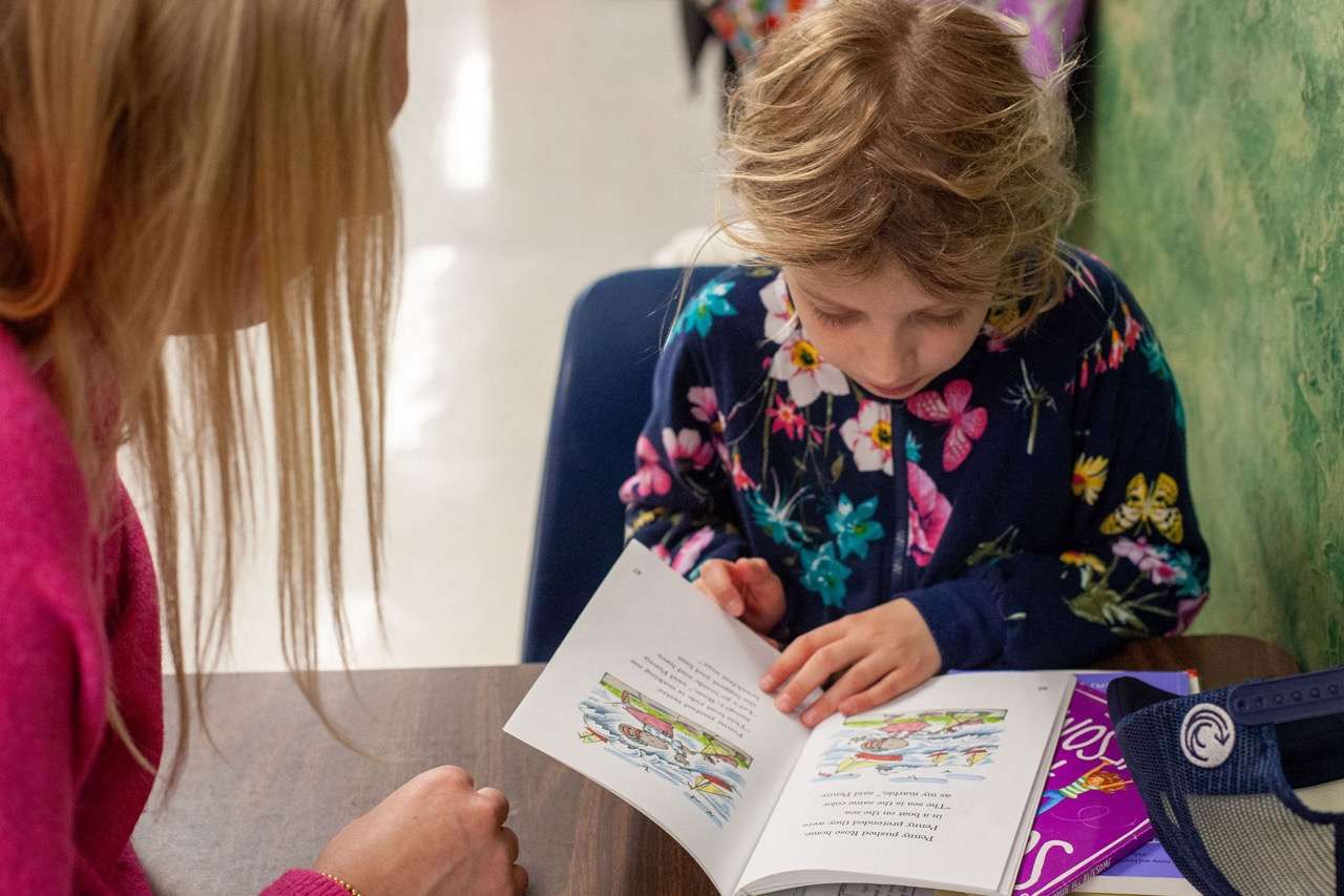 A volunteer and student sharing a book