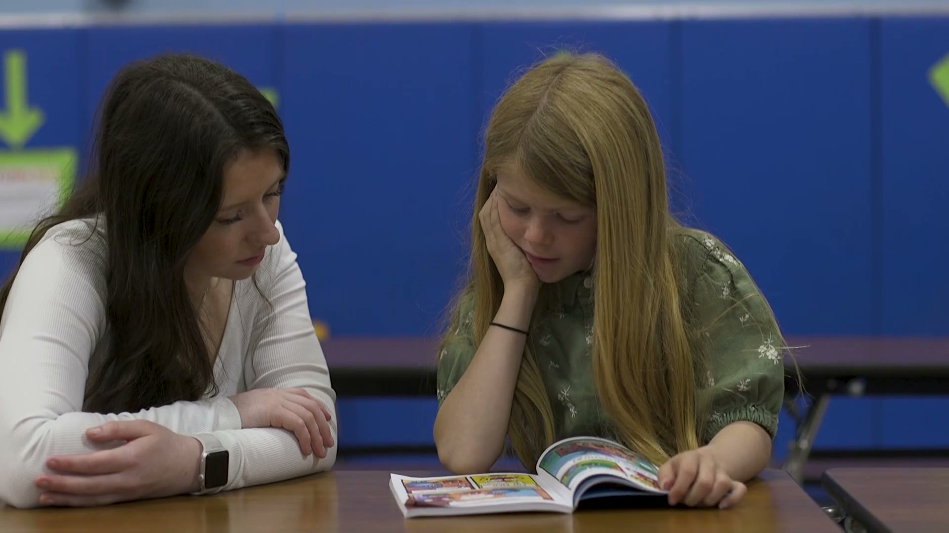 A ROW volunteer sharing a book with a student